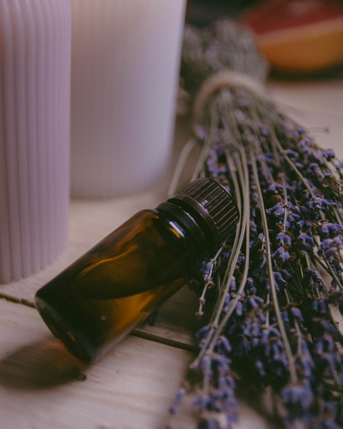 Calming lavender, essential oil bottle, and candles for aromatherapy on a wooden surface.